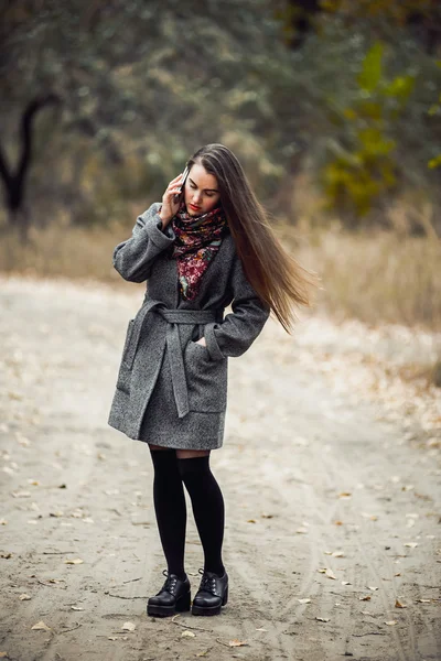 Jovem menina bonita com telefone celular andando no parque — Fotografia de Stock