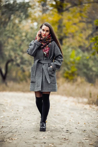 Jovem menina bonita com telefone celular andando no parque — Fotografia de Stock