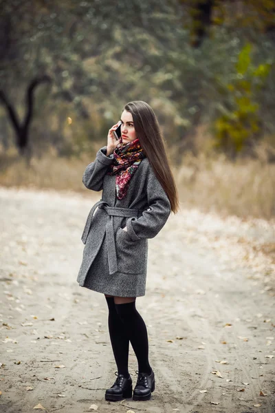 Jovem menina bonita com telefone celular andando no parque — Fotografia de Stock