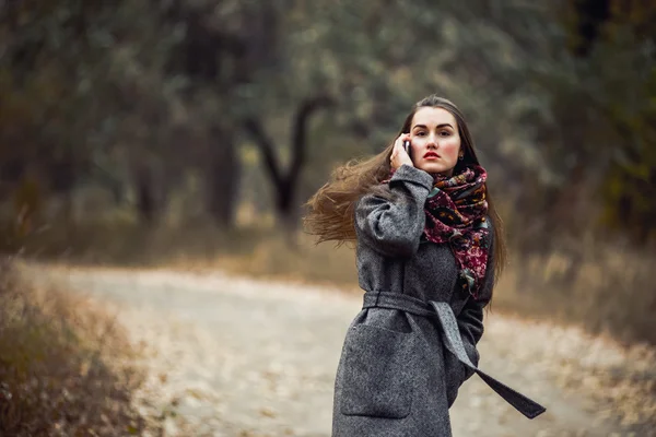 Jovem menina bonita com telefone celular andando no parque — Fotografia de Stock