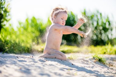 Kum havuzunda oynayan küçük tombul yürümeye başlayan çocuk güneşli havalarda yaz