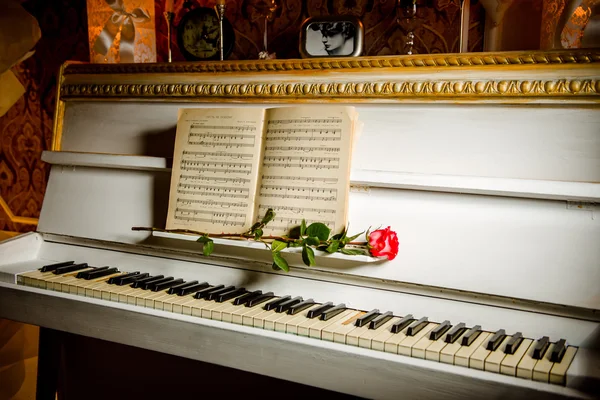 Rosa vermelha em teclas de piano e livro de música — Fotografia de Stock