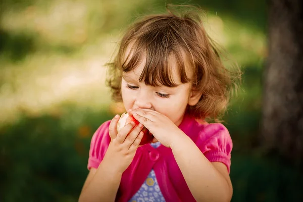 Schattige kleine meisje eten apple in het park — Stockfoto