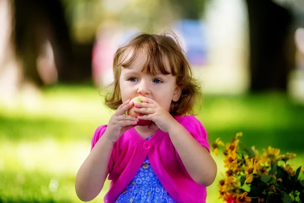 Linda niña comiendo manzana en el parque —  Fotos de Stock