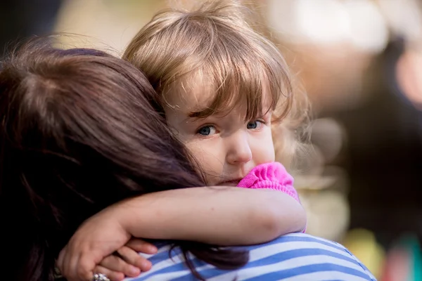 Klein meisje haar moeder in een park close-up knuffelen — Stockfoto