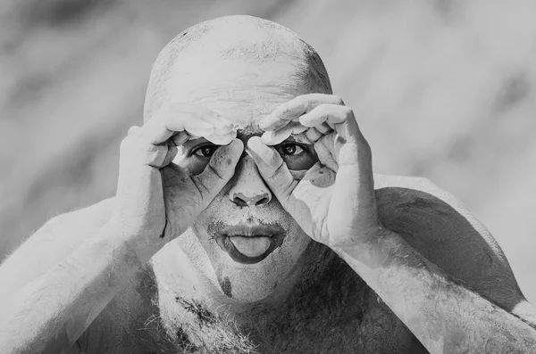 Retrato de um homem no barro, mostrando a língua . — Fotografia de Stock