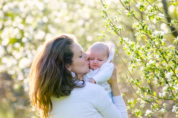 Menino com sua jovem mãe no jardim de flores — Fotografia de Stock