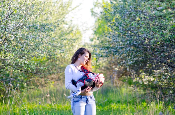 Liten pojke med sin unga mor i blossom trädgården — Stockfoto