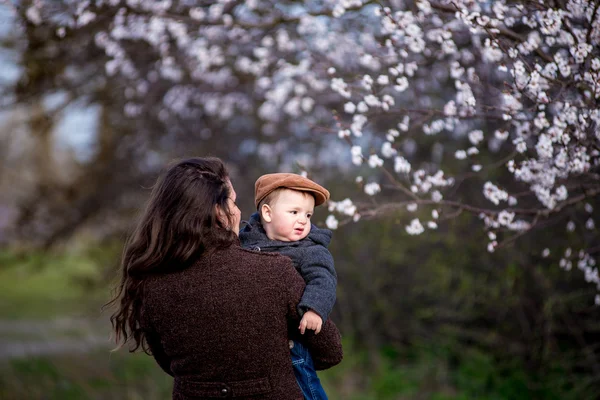 Kleine babyjongen met haar jonge moeder in de tuin van de bloesem — Stockfoto