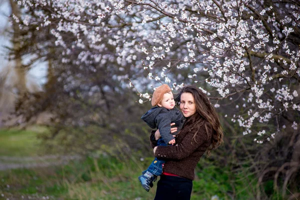 Kleine babyjongen met haar jonge moeder in de tuin van de bloesem — Stockfoto