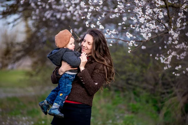 Kleine babyjongen met haar jonge moeder in de tuin van de bloesem — Stockfoto