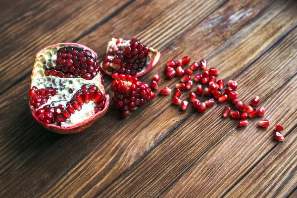 Fruta de romã madura com fatias de romã em uma mesa de madeira closeup . — Fotografia de Stock