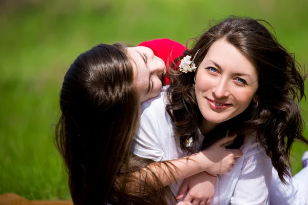 Daughter with the mother sitting on the grass and talking — Stock Photo, Image