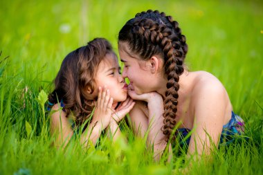 İki kız kardeş çim ve sevimli gülümseme üzerinde yalan