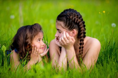 İki kız kardeş çim ve sevimli gülümseme üzerinde yalan