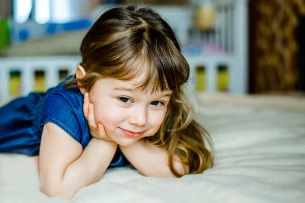 Очаровательная улыбающаяся маленькая девочка проснулась в своей постели — стоковое фото