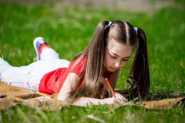 Hermosa niña dibuja en lápices de la naturaleza — Foto de Stock