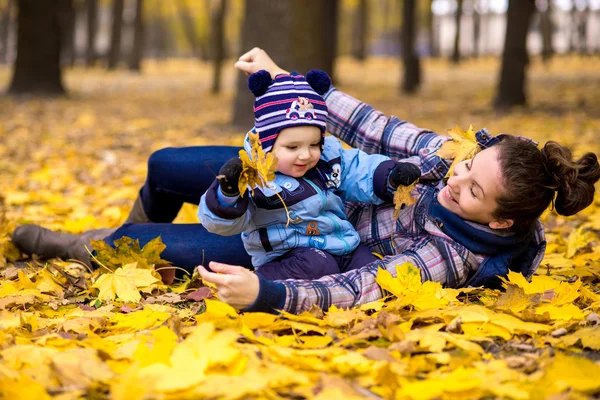 Feliz joven hermosa madre con su pequeño hijo en el parque en otoño — Foto de Stock