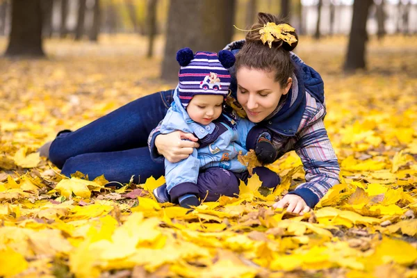 Счастливая молодая красивая мать с маленьким сыном в парке осенью — стоковое фото