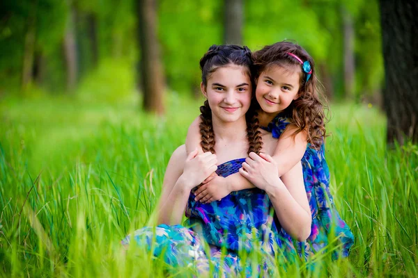 Two sisters lying on the grass and cute smile — Stock Photo, Image