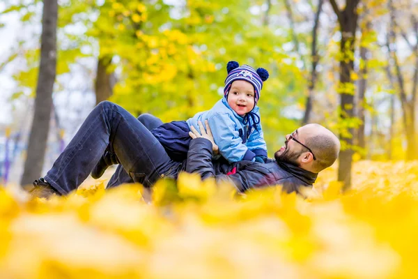 Счастливый отец и сын играют вместе, веселясь в осеннем парке — стоковое фото