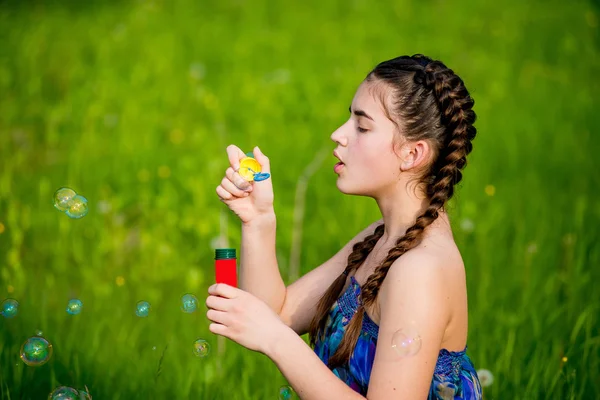 Маленькі дівчата дме бульбашки, що сидять на траві — стокове фото