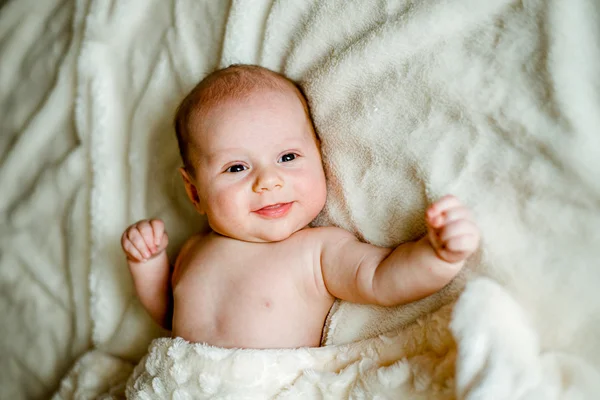 Bebê em um boné de malha é coberto com um cobertor — Fotografia de Stock