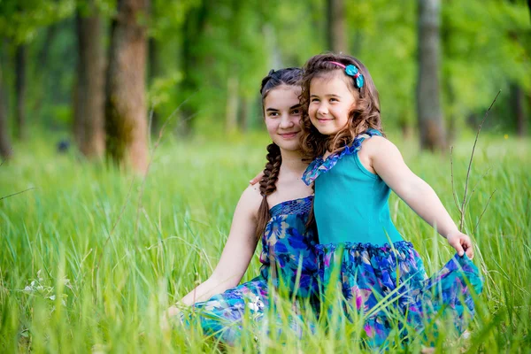 Duas irmãs deitadas na grama e sorriso bonito — Fotografia de Stock