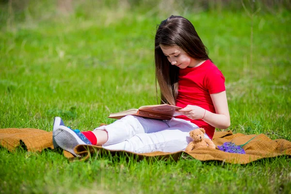 Menina adorável no parque de verão livro de leitura — Fotografia de Stock