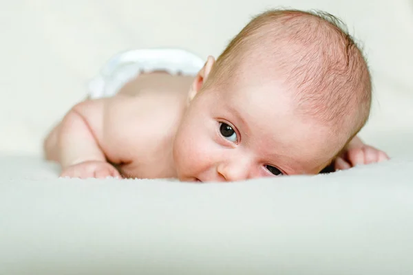 Newborn baby lying with open eyes in crib — Stock Photo, Image