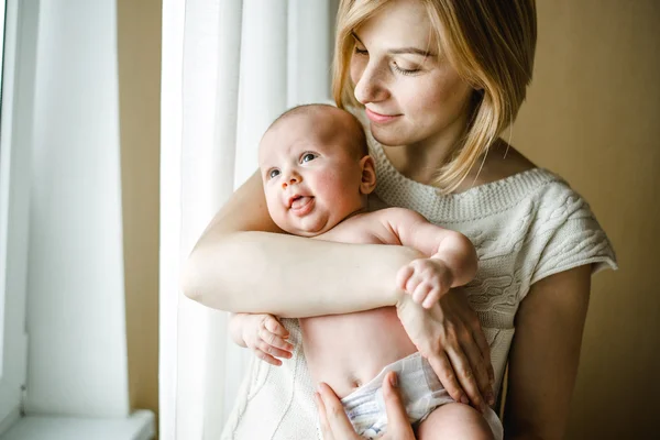 ウィンドウ時の母の優しい抱擁で生まれたばかりの赤ちゃん — ストック写真