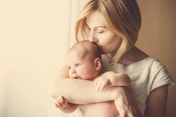 Bebê recém-nascido em um abraço terno da mãe na janela — Fotografia de Stock