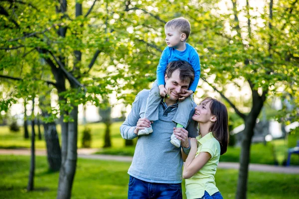 Feliz familia joven se encuentra cerca de un árbol floreciente y sonriente — Foto de Stock