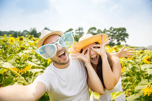 幸せなカップルの若い男性と女性は、ひまわり、作る selfie 写真のフィールド — ストック写真