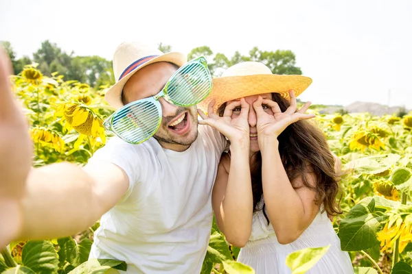 幸せなカップルの若い男性と女性は、ひまわり、作る selfie 写真のフィールド — ストック写真