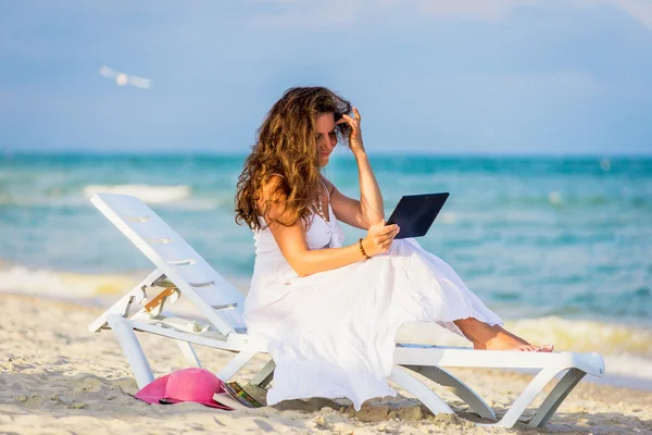 Mujer joven en sombrero con tablet pc en la playa — Foto de Stock