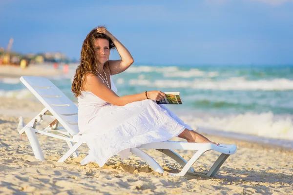 Mujer joven leyendo un libro en la playa — Foto de Stock