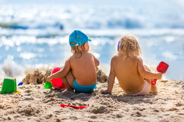 Denizin kenarında sahilde sıcak bir günde oynayan çocuklar — Stok fotoğraf