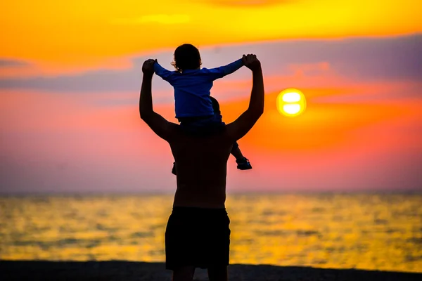 Padre arrojando a su hijo en el aire en la playa, silueta disparada — Foto de Stock