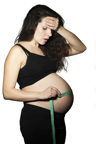 Den mäter den gravida magen centimeter på en vit bakgrund — Stockfoto