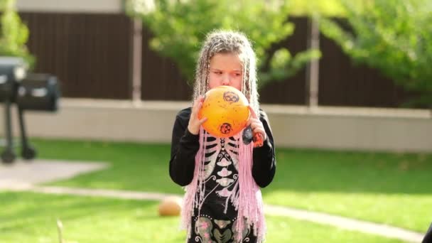 La famille décore la maison pour Halloween. Enfants habillés comme un squelette d'une chauve-souris soufflant un ballon avec une photo d'un nid de citrouille. — Video