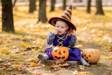 Mutlu Cadılar Bayramı! Balkabaklı sevimli küçük cadı. Dışarıda takım elbiseli güzel bir kız çocuğu..
