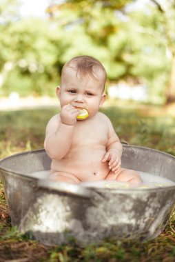 Eski moda metal küvetteki şirin bebek parkta limon parçasıyla oynuyor.