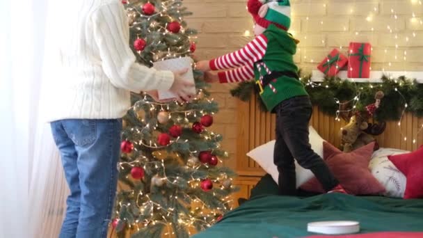 Mãe feliz e pequeno filho bonito decorar árvore de Natal juntos — Vídeo de Stock