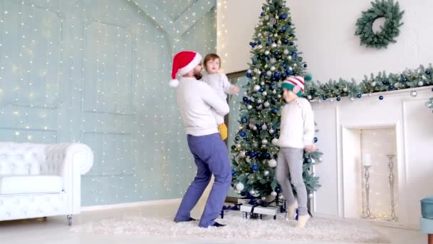 Papà balla con il suo piccolo figlio mentre si gode il Natale insieme in una stanza decorata a casa con luci accese e un albero di Natale. — Video Stock