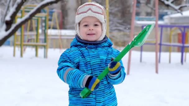 Un niño pequeño camina en el patio en invierno. Niño jugando y sonriente en la nieve blanca esponjosa. Actividades de ocio y juegos. — Vídeos de Stock