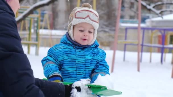 Маленький ребенок ходит по двору зимой. Играет и улыбается ребенок на белом пушистом снегу. Развлечения и игры. — стоковое видео