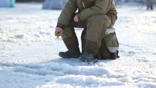 Egy halász horgászik egy rúdon egy jégveremben egy téli halásztavon.. — Stock videók