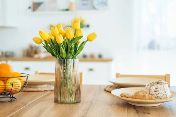 Yellow tulips in a vase on the table. Spring holiday, Easter, home decor.