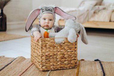 Tavşan kostümlü komik bir çocuk sepette oturuyor. Paskalya tavşanı. Paskalya kutlaması